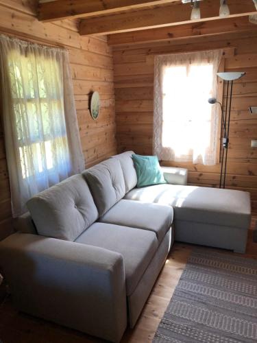 a living room with a couch and two windows at Juniper holiday house in Kassari with sauna in Hiiumaa