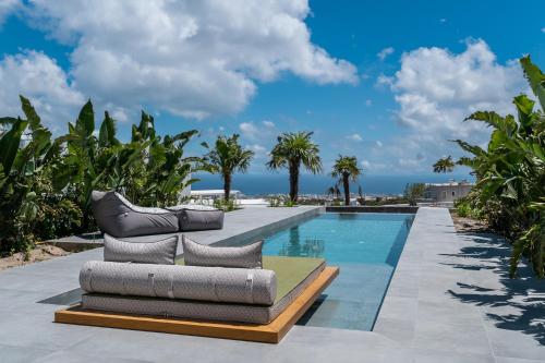 uma piscina com duas espreguiçadeiras ao lado de uma piscina em Numa Santorini em Fira