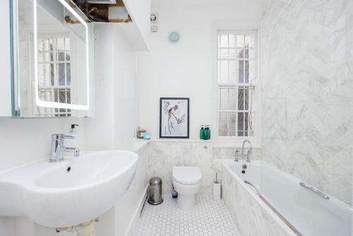 a white bathroom with a sink and a tub and a toilet at Dynamic in Dean Street in London