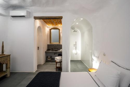 - une chambre avec des murs blancs, un lit et un lavabo dans l'établissement Numa Santorini, à Fira