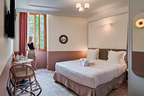 Aparthotel AMMI Vieux Nice في نيس: امرأة تقف في غرفة الفندق مع سرير