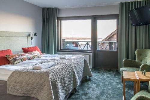 a bedroom with a bed and a chair and a window at Green Hotel in Tällberg