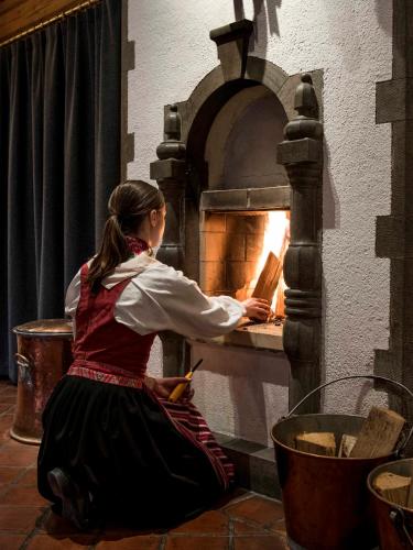a woman is putting a pizza into an oven at Green Hotel in Tällberg