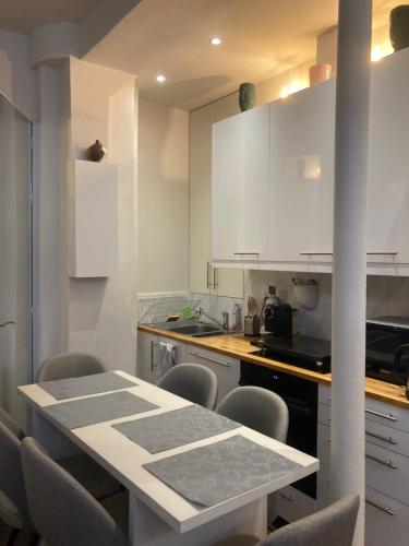 une cuisine avec des armoires blanches et une table et des chaises dans l'établissement Appartement Villiers, à Paris