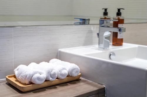 une pile de serviettes sur une planche de découpe à côté d'un lavabo dans l'établissement Voyage One Bedroom In Reem Island, à Abu Dhabi