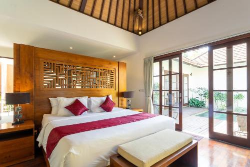 een slaapkamer met een groot bed met rode kussens bij Sukanami Villa Ubud by ecommerceloka in Gianyar