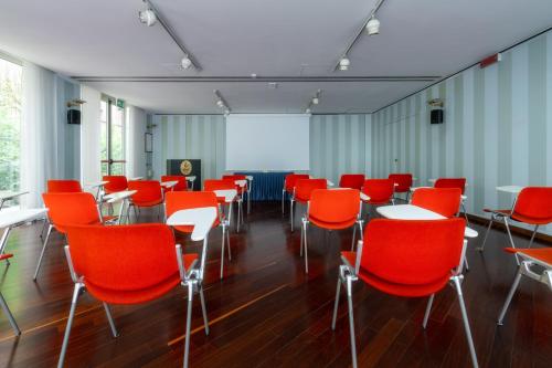 a room with red chairs and tables and a screen at Hotel Crivi's in Milan
