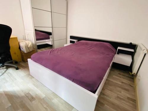 1 dormitorio con 1 cama con manta morada en Maison familiale proche plage et commerces, en Saint-Nazaire