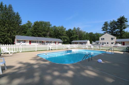 a swimming pool with a white fence and a house at The Villager Motel in Bartlett