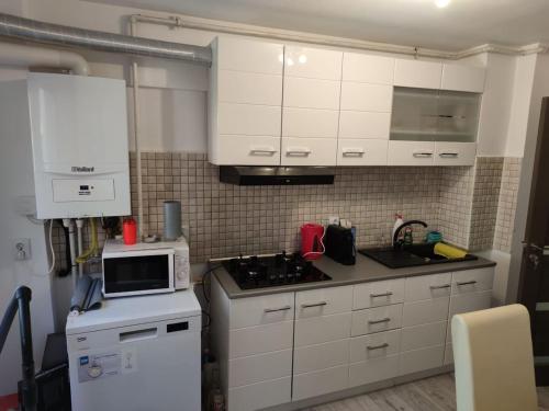 a kitchen with white cabinets and a stove and a microwave at Natura Slanic Moldova in Slănic-Moldova