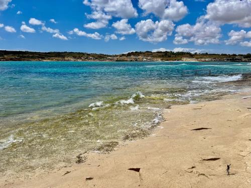 a beach with blue water and clouds in the sky at Peaman Court in Marsaskala