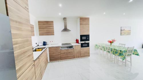 a kitchen with wooden cabinets and a dining table at Peaman Court in Marsaskala