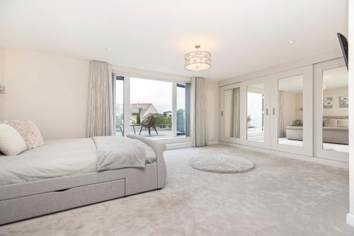ein weißes Schlafzimmer mit einem Bett und einem großen Fenster in der Unterkunft Luxury home with Harbour Views in Poole in Poole