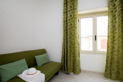 Una sala de estar con un sofá verde y una ventana. en Casa Bata by Wonderful Italy, en Budoni