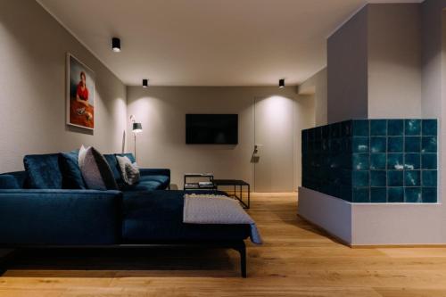 a living room with a blue couch and a tv at Appart Hotel Knappaboda in Lech am Arlberg