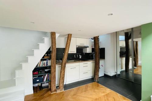 une cuisine avec des armoires blanches et un escalier dans l'établissement Bright duplex on the top floor - close to Opera, à Paris
