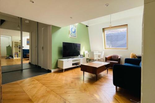 un salon avec un canapé et une télévision dans l'établissement Bright duplex on the top floor - close to Opera, à Paris