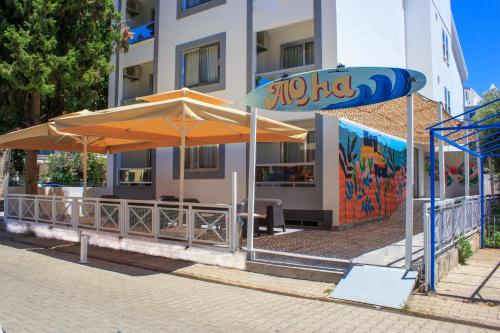 a building with umbrellas in front of a building with a surfboard at Aloha Suites in Marmaris