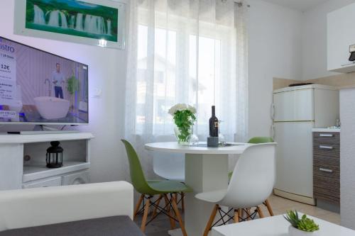 a white kitchen with a white table and green chairs at Apartments Pasalic in Kaštela