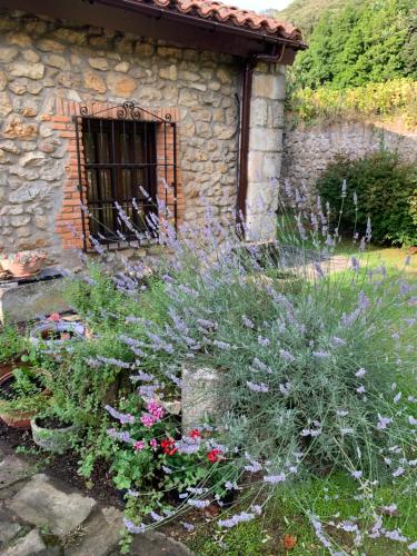 a garden with flowers in front of a stone building at Casa Rural Erre Q Erre in Oreña