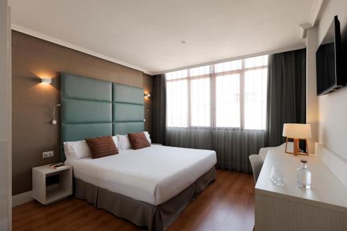 a hotel room with two beds and a television at Hotel Pax Guadalajara in Guadalajara
