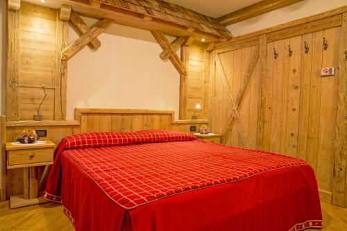 a red bed in a room with wooden walls at Hotel Malder in Soraga
