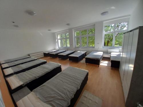a large room with several beds and windows at Márianosztrai Zarándokszálláshely in Márianosztra