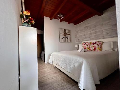 een slaapkamer met een wit bed en een houten vloer bij Estudio Agradable, Con Jacuzzi, Terraza y Barbacoa, Totalmente independiente in Corralejo