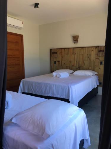 two beds in a hotel room with white sheets at Barong EcoVilla in Barra Grande