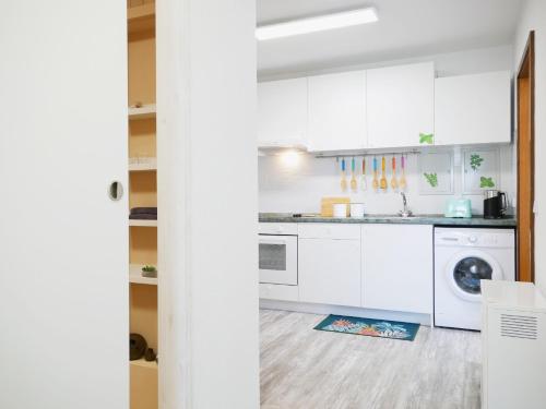 a kitchen with white cabinets and a washer and dryer at Ferienwohnung mit Garten in Ehrenkirchen