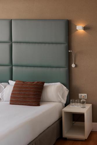 a bed with a blue headboard and a side table at Hotel Pax Guadalajara in Guadalajara