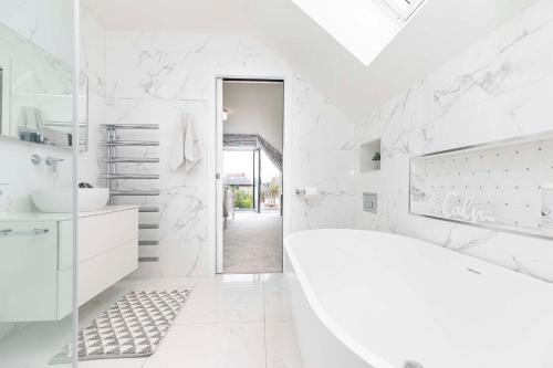 ein weißes Badezimmer mit einer Badewanne und einem Waschbecken in der Unterkunft Luxury home with Harbour Views in Poole in Poole