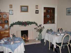 uma sala de jantar com duas mesas e uma lareira em Dunroamin Hotel em Bonar Bridge