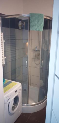 a washing machine in a bathroom with a shower at Apartament Sea Planet Mielno Centrum - parking w cenie pobytu in Mielno