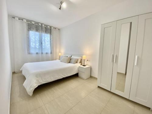 um quarto branco com uma cama branca e uma janela em Apartamento con piscina Sant Carles de la Ràpita em Sant Carles de la Ràpita