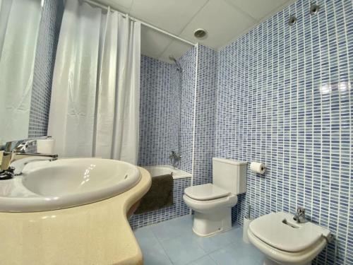 uma casa de banho em azulejos azuis com um lavatório e um WC em Apartamento con piscina Sant Carles de la Ràpita em Sant Carles de la Ràpita