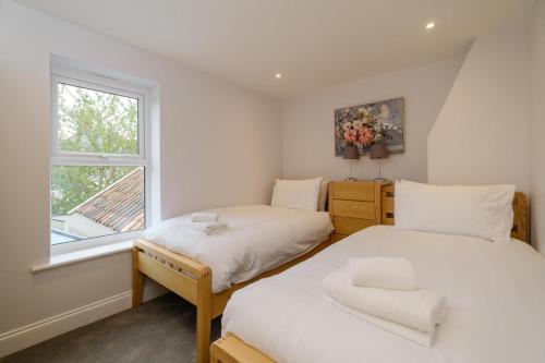 two beds in a small room with a window at Primrose Cottage in Leiston