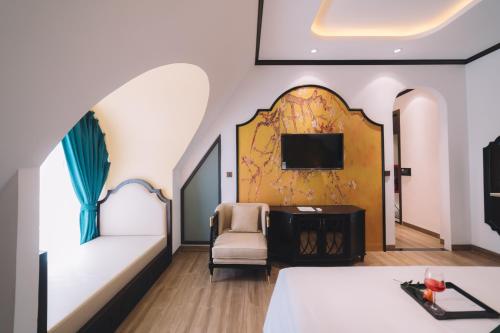 een kamer met een bed, een stoel en een tv bij Goldient Boutique Hotel in Da Lat