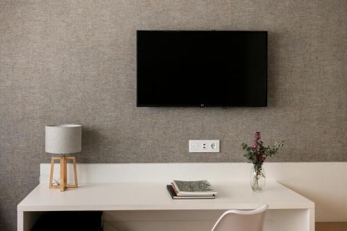 a tv on a wall with a white desk with a lamp at Hotel Pax Guadalajara in Guadalajara