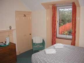 1 dormitorio con cama, ventana y silla en Dunroamin Hotel en Bonar Bridge