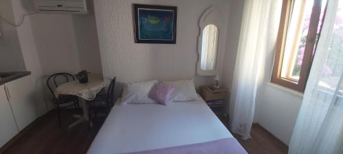 a small bedroom with a white bed and a table at Vila Dora Supetar in Supetar