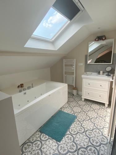 a bathroom with a tub and a sink and a skylight at La LocaLuna in Civray-de-Touraine