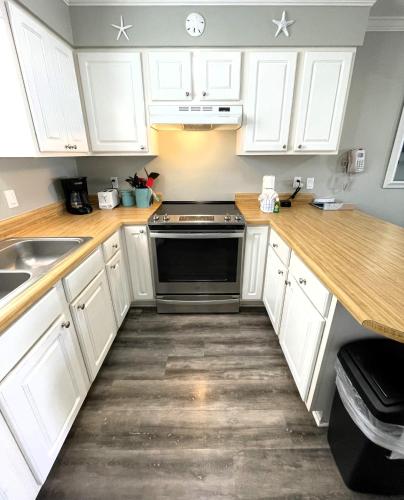 a kitchen with white cabinets and a stove top oven at LIVE ON ISLAND TIME! GREAT GULF SHORES BEACH CONDO, VERY NICE in Gulf Shores