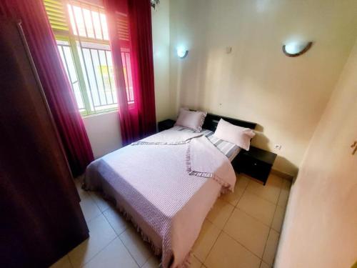 a bedroom with a bed with pink sheets and a window at TWINS VILLA SUITES KIGALI in Kigali