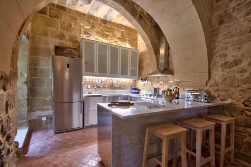 a kitchen with a refrigerator and a stone wall at Casa Mezzodì' - Luxurious 18th C. Farmhouse with Gardens & Pool in Kerċem