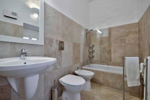 y baño con lavabo, aseo y bañera. en Casa Mezzodì' - Luxurious 18th C. Farmhouse with Gardens & Pool, en Kerċem