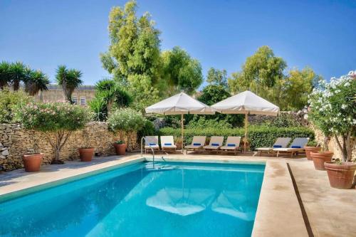 a swimming pool with lounge chairs and umbrellas at Casa Mezzodì' - Luxurious 18th C. Farmhouse with Gardens & Pool in Kerċem