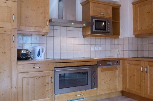 - une cuisine avec des placards en bois et un four micro-ondes dans l'établissement Montseti - 3 bedroom ski-in ski-out apartment, à Sainte-Foy-Tarentaise