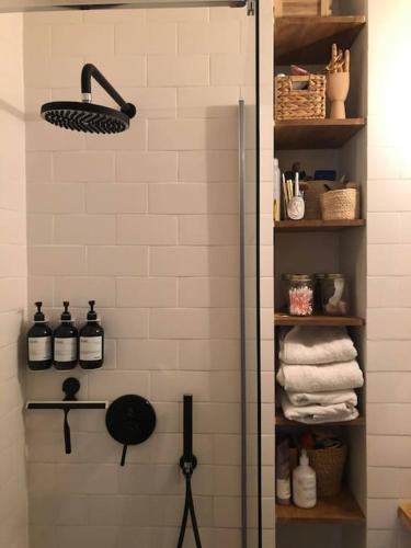 une salle de bain avec une cabine de douche avec des bouteilles et des serviettes dans l'établissement Appartement 75009 PARIS 50m2 métro poissonnière 3 pers & baby, à Paris