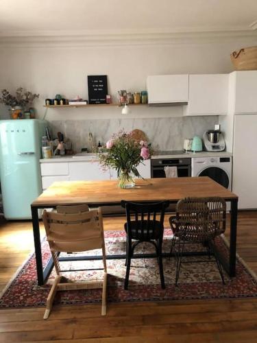 une cuisine avec une table en bois et deux chaises dans l'établissement Appartement 75009 PARIS 50m2 métro poissonnière 3 pers & baby, à Paris